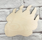 A light natural wood bear paw silhouette wall decor piece with visible wood grain, displayed against a white painted brick wall background.