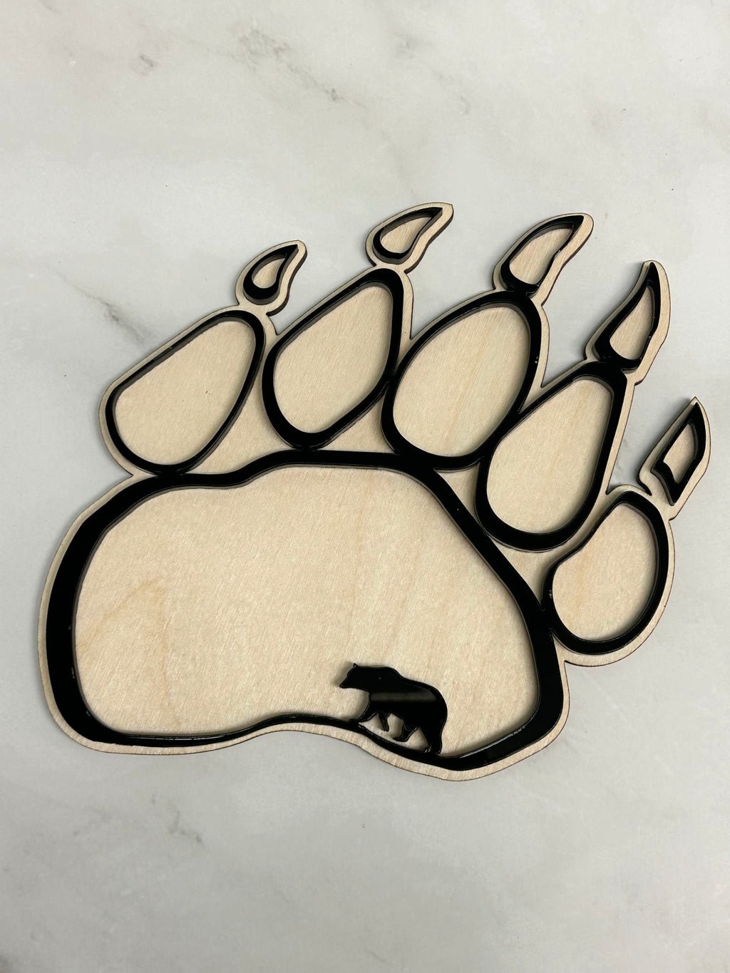 Wooden bear paw print decoration on a white marble background